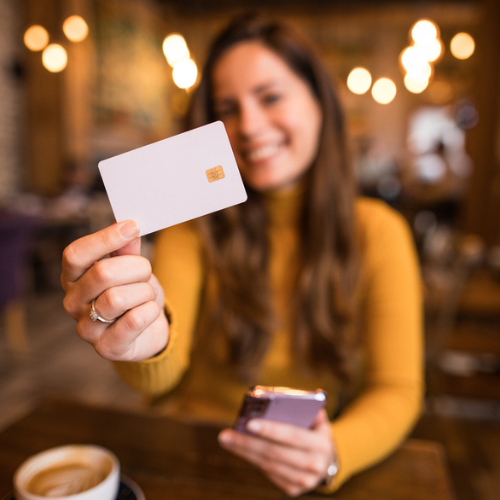 kvinna som håller fram ett kreditkort